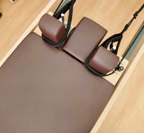 Close-up of brown reformer carriage padding, cushions and straps