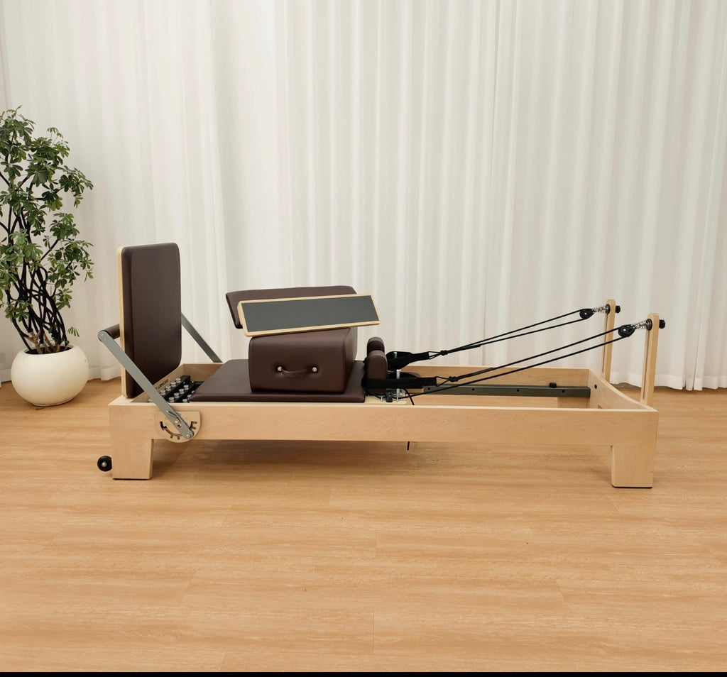 Maple wood Pilates reformer with brown upholstery in a bright room